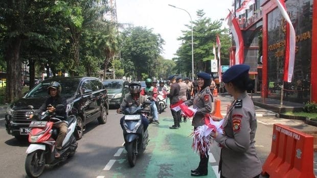 Sambut HUT RI ke-80, Brimob Polda Metro Bagikan Ribuan Bendera Merah Putih ke Warga