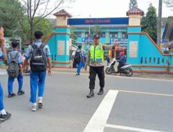 Personil Polsek Sulang Bantu Anak-anak Sekolah Menyeberang Jalan Dengan Aman