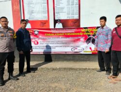 Bhabinkamtibmas Desa Emplak Briptu M agung memasang spanduk mengenai TPPO